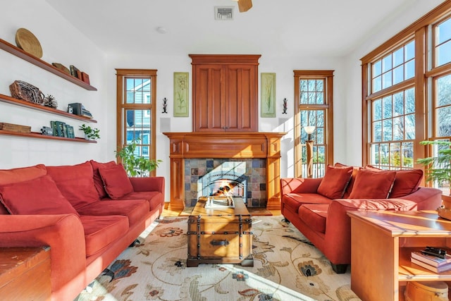 living room featuring a wealth of natural light, visible vents, and a tiled fireplace