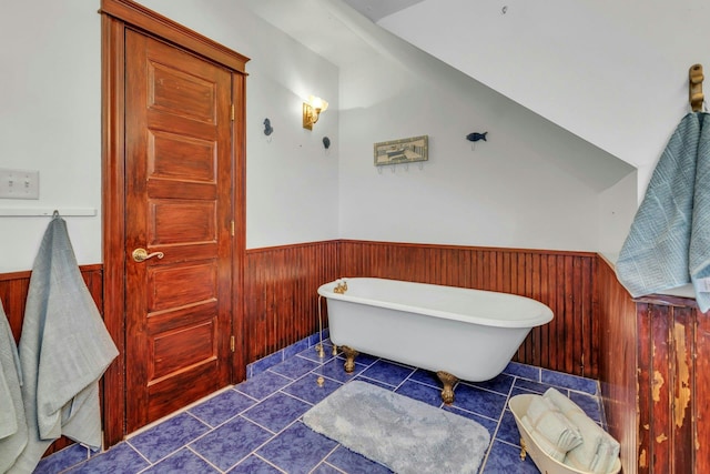 bathroom with tile patterned floors, wainscoting, wood walls, and a freestanding tub