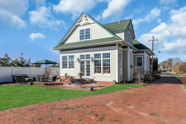 rear view of property with a patio, fence, a lawn, and roof with shingles