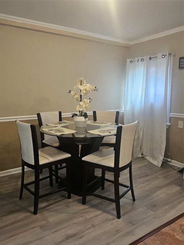 dining area with baseboards, wood finished floors, and ornamental molding