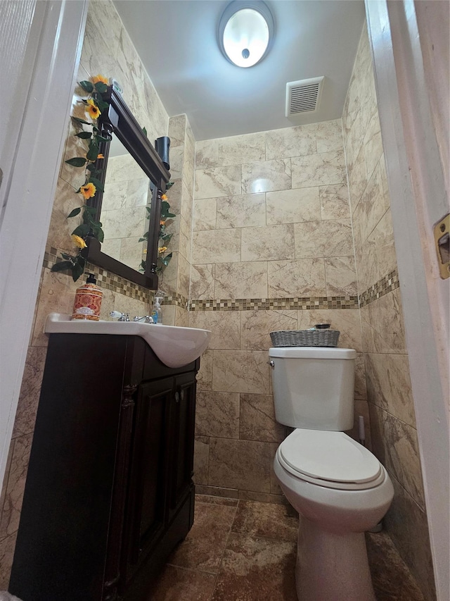 bathroom with visible vents, toilet, tile walls, and vanity