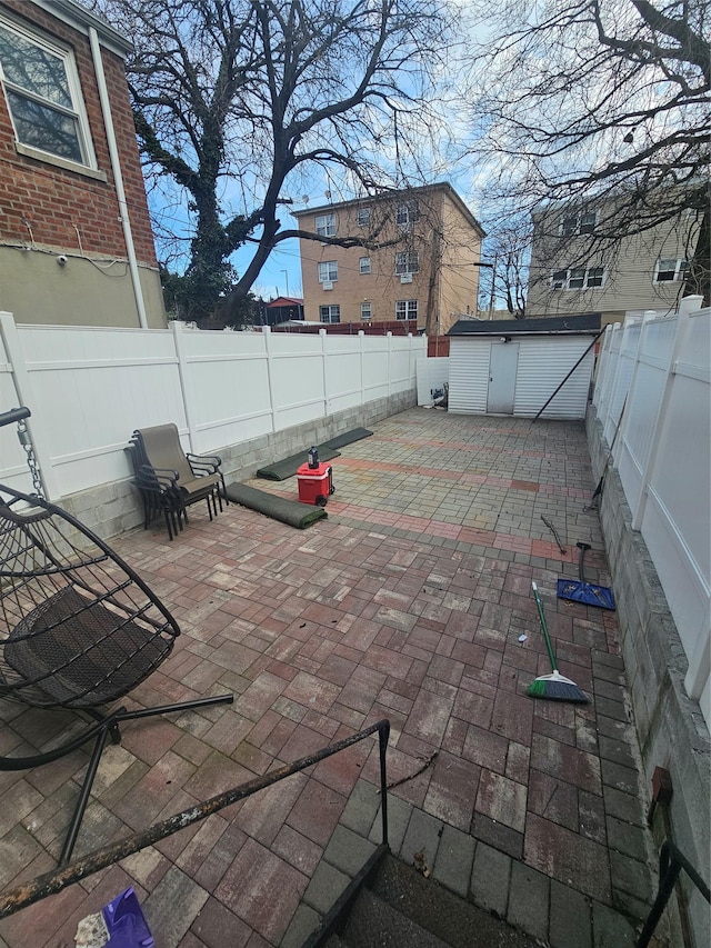 view of patio / terrace with an outbuilding, a storage shed, and a fenced backyard