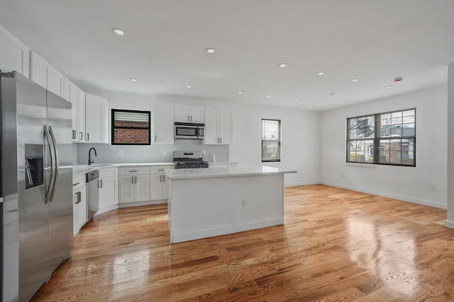 139-19 230th St, Laurelton, NY 11413 - kitchen featuring a center island, white cabinets, appliances with stainless steel finishes, light wood finished floors, and a sink