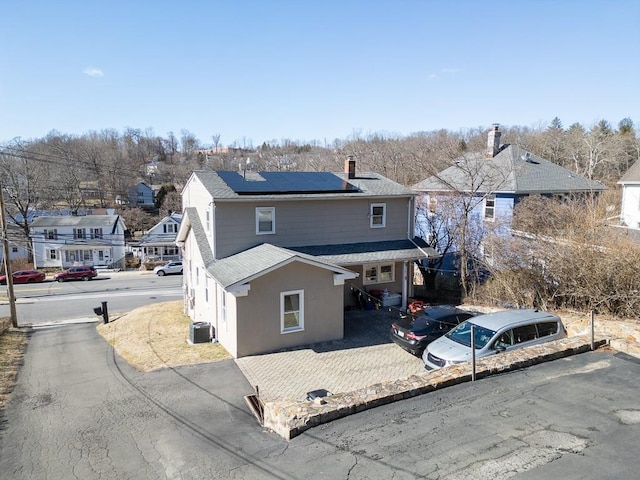 view of front of property with stucco siding, a residential view, roof with shingles, and solar panels