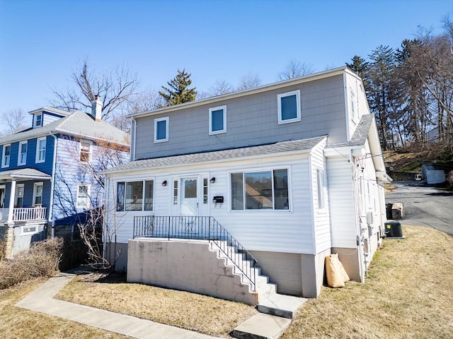 view of front of home featuring a front lawn and roof with shingles