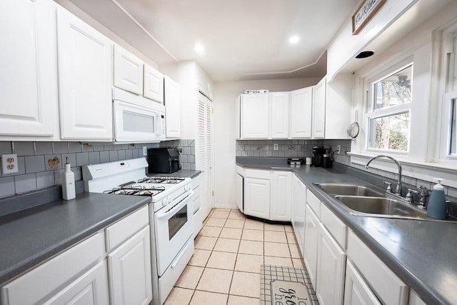 kitchen featuring a sink, dark countertops, white appliances, white cabinets, and light tile patterned floors