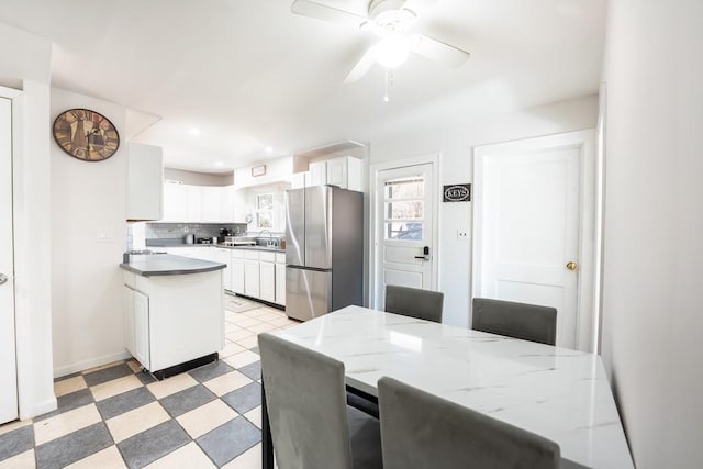 dining room with light floors, baseboards, and a ceiling fan