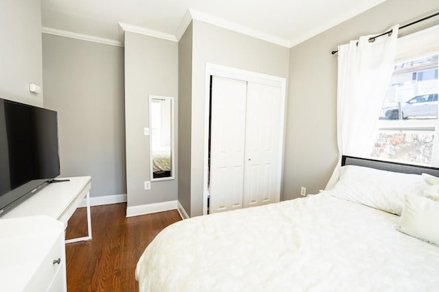 bedroom with a closet, crown molding, dark wood-type flooring, and baseboards