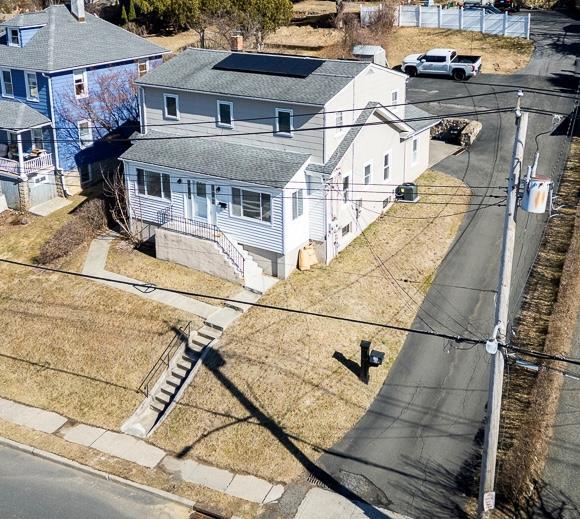 view of front facade featuring solar panels and a shingled roof