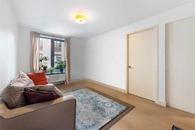 living area with cooling unit, baseboards, and light wood finished floors