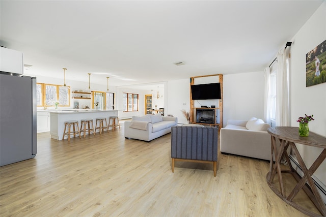 living area with visible vents, baseboard heating, and light wood finished floors