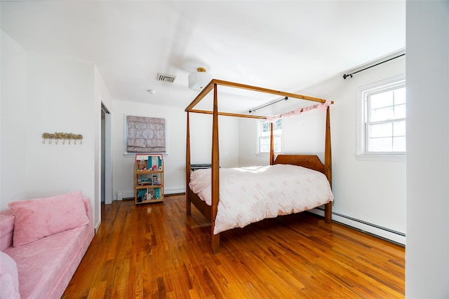 bedroom featuring a baseboard heating unit, visible vents, and hardwood / wood-style floors