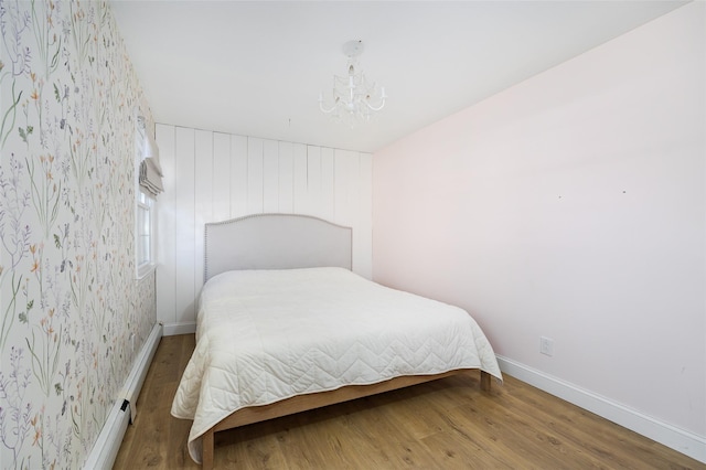 bedroom with a chandelier, baseboards, and wood finished floors