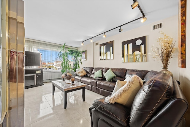 living area featuring rail lighting, light tile patterned floors, and visible vents