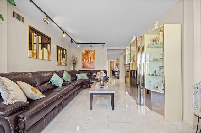 living area with track lighting, light tile patterned floors, and visible vents