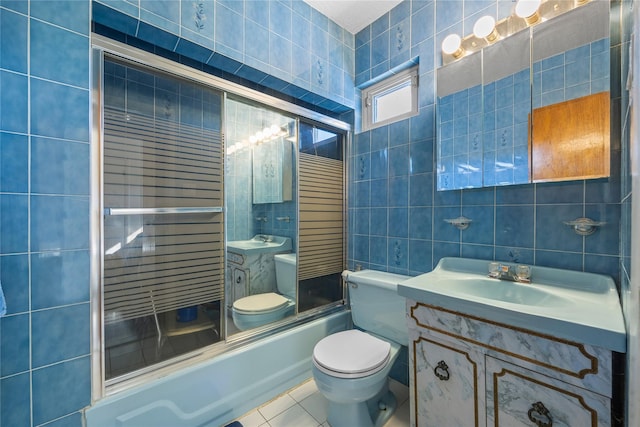 full bathroom featuring tile patterned floors, toilet, tile walls, bath / shower combo with glass door, and vanity