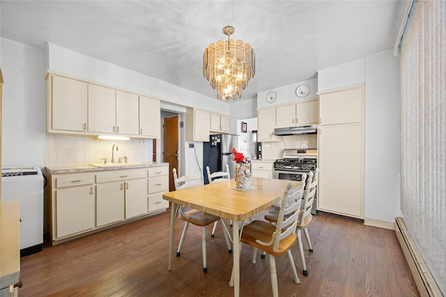 kitchen featuring wood finished floors, a sink, stainless steel appliances, under cabinet range hood, and a baseboard heating unit