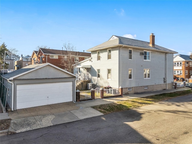 exterior space featuring a detached garage, fence, a residential view, a chimney, and an outdoor structure