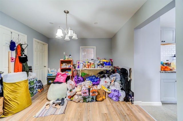 playroom featuring baseboards, an inviting chandelier, and wood finished floors