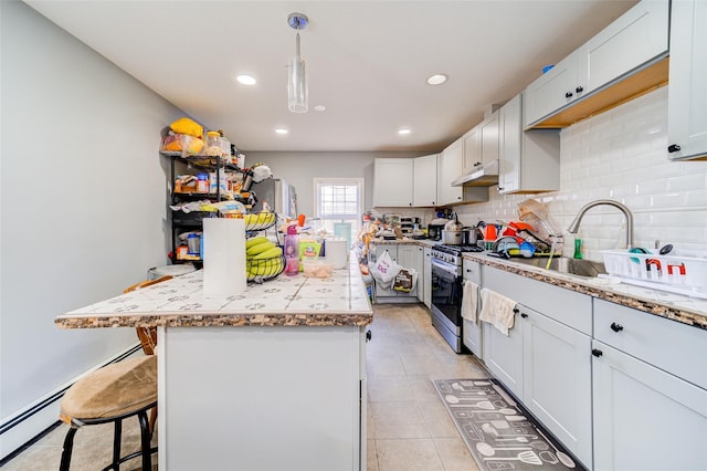 kitchen featuring a kitchen bar, a sink, tasteful backsplash, recessed lighting, and gas range