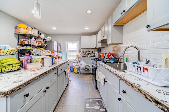 kitchen featuring light countertops, backsplash, light tile patterned flooring, and appliances with stainless steel finishes