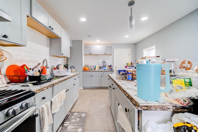 kitchen featuring pendant lighting, wall chimney exhaust hood, light tile patterned flooring, decorative backsplash, and gas range