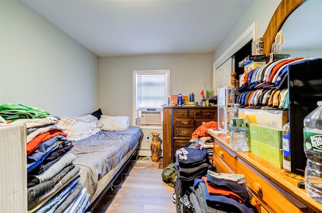 bedroom with cooling unit and wood finished floors