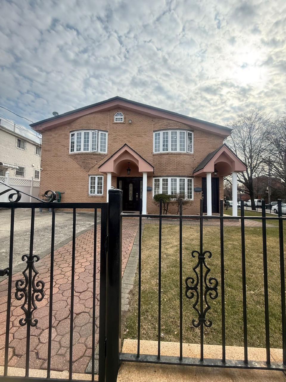 view of front facade featuring a front lawn, a gate, brick siding, and a fenced front yard