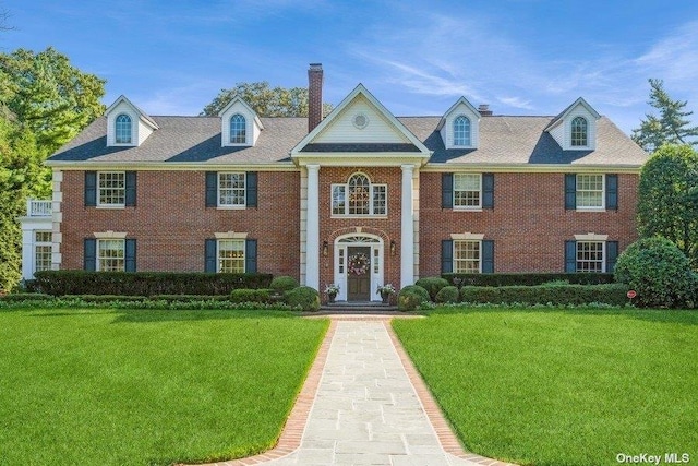 neoclassical / greek revival house with a front yard and brick siding