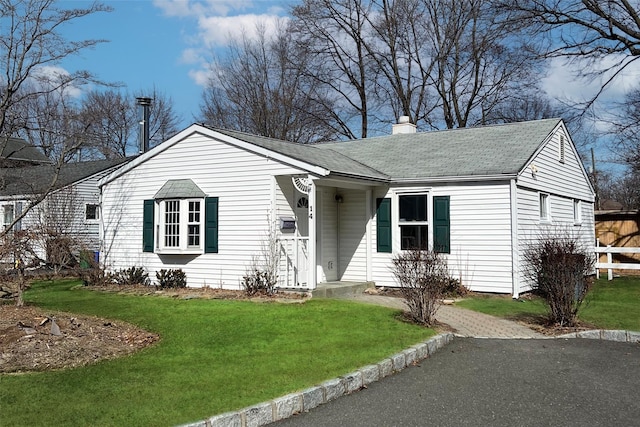 single story home featuring roof with shingles, a chimney, and a front yard