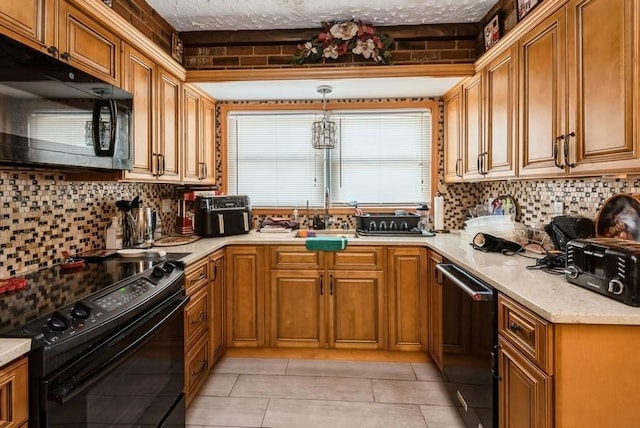 kitchen featuring light countertops, decorative backsplash, brown cabinetry, black appliances, and a sink