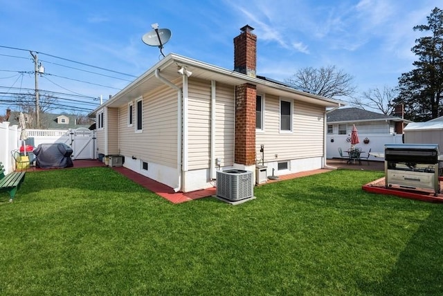 rear view of house featuring a yard, central AC unit, a chimney, and fence