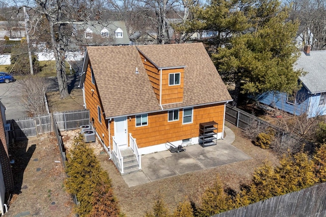 back of house featuring central air condition unit, roof with shingles, and a fenced backyard