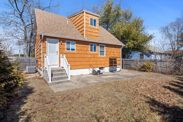 rear view of house featuring central air condition unit, a shingled roof, and fence