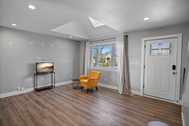 living area with vaulted ceiling with skylight, recessed lighting, wood finished floors, and baseboards