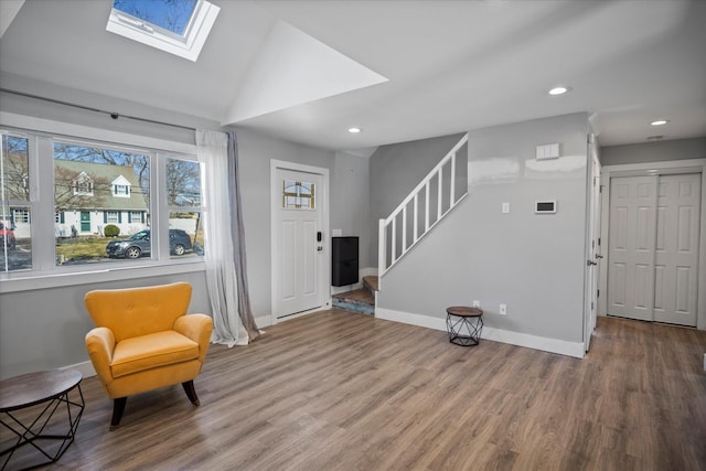 sitting room featuring stairway, wood finished floors, baseboards, vaulted ceiling with skylight, and recessed lighting