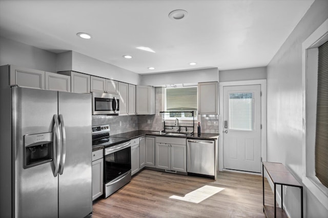 kitchen featuring dark countertops, gray cabinetry, wood finished floors, and stainless steel appliances