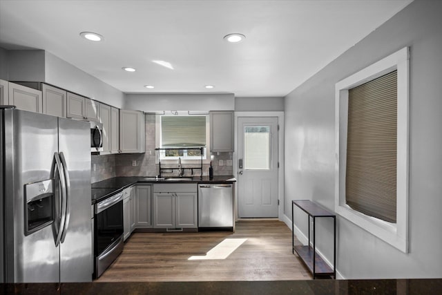 kitchen featuring decorative backsplash, dark countertops, appliances with stainless steel finishes, and gray cabinetry