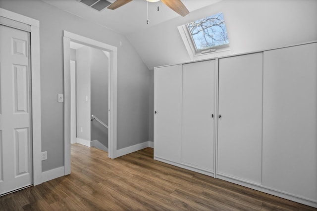 unfurnished bedroom featuring visible vents, vaulted ceiling with skylight, wood finished floors, and a ceiling fan