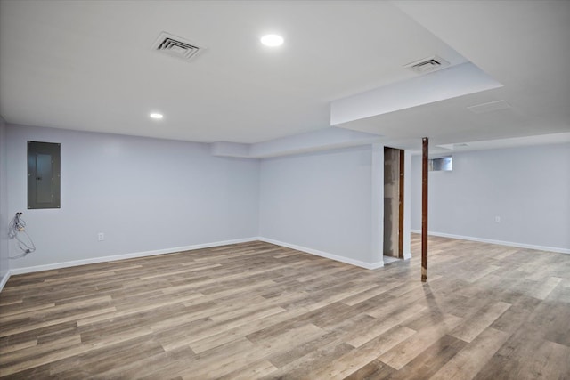 finished basement featuring electric panel, visible vents, baseboards, and wood finished floors