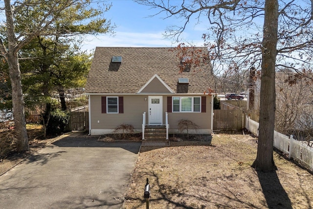 view of front facade with a shingled roof and fence