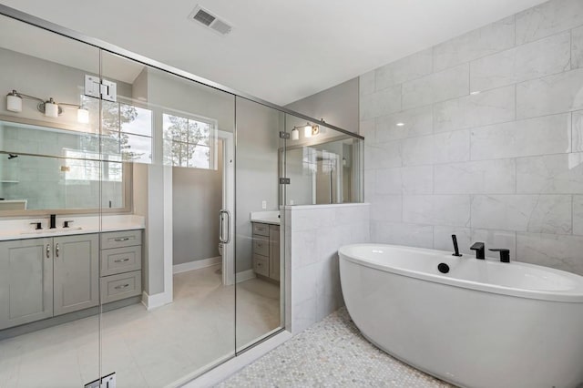 bathroom featuring vanity, tile walls, visible vents, and a shower stall