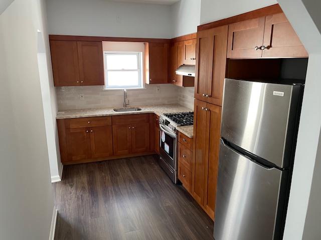 kitchen featuring brown cabinets, stainless steel appliances, light countertops, and a sink