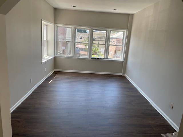 spare room featuring dark wood-style floors and baseboards