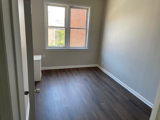 spare room with baseboards and dark wood finished floors