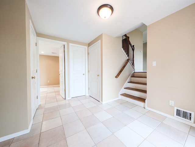 unfurnished room with visible vents, stairway, and baseboards