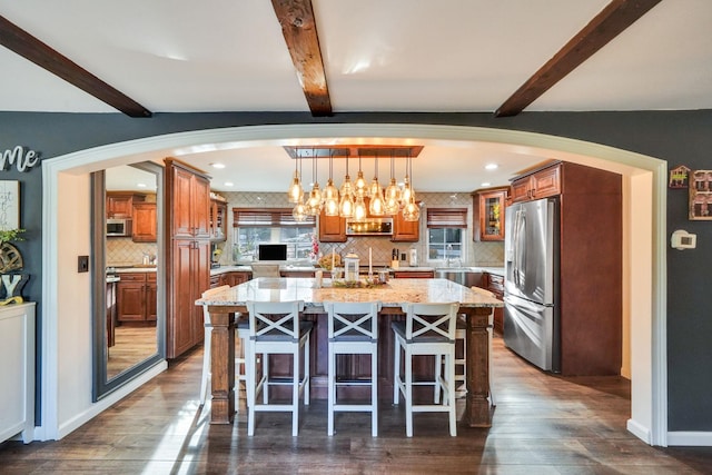 kitchen with light stone counters, a kitchen breakfast bar, appliances with stainless steel finishes, and a wealth of natural light