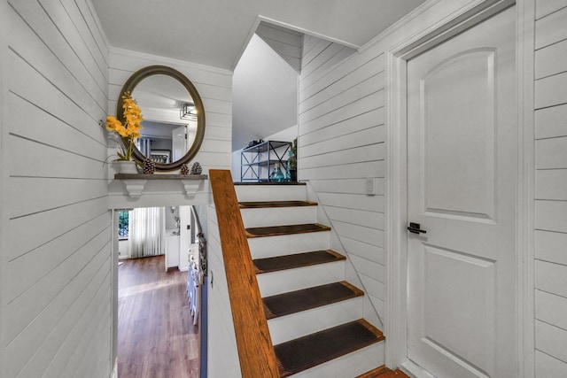 stairs featuring wood finished floors and wood walls