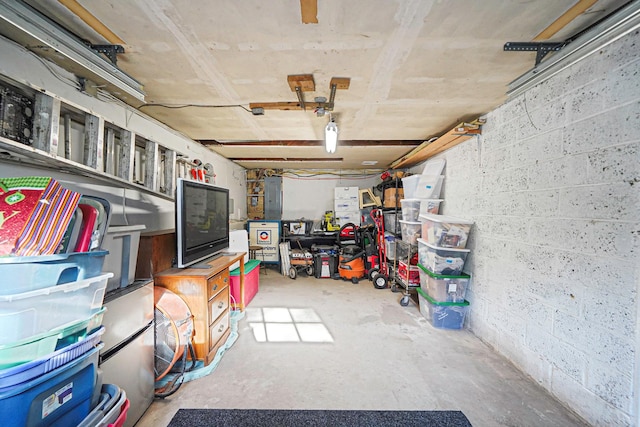 interior space featuring electric panel, a garage, and concrete block wall