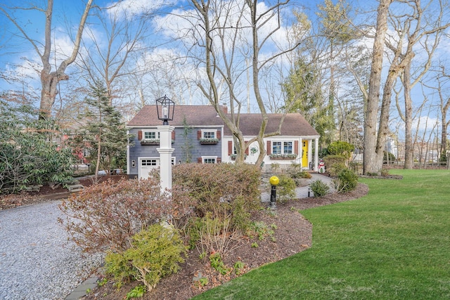 view of front facade featuring a garage, a chimney, gravel driveway, and a front yard